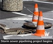 A photo of orange construction cones at a sewer cover.
