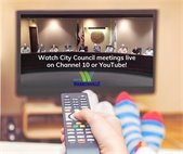 A photo of someone with their feet up and aiming the remote control at the TV to promote watching City Council meetings live.