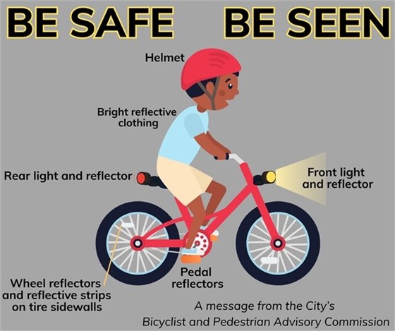 A boy riding a bicycle safely with helmet, pedal reflectors, front and back lights.