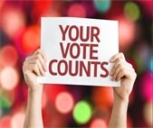 A photo of someone holding a sign that says "Your Vote Counts" to promote the November 5 General Election.